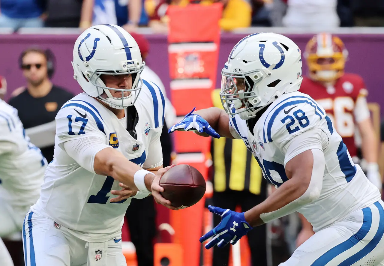 Indianapolis Colts' quarterback Daniel Jones (L) hands off to team mate Jonathan Taylor 