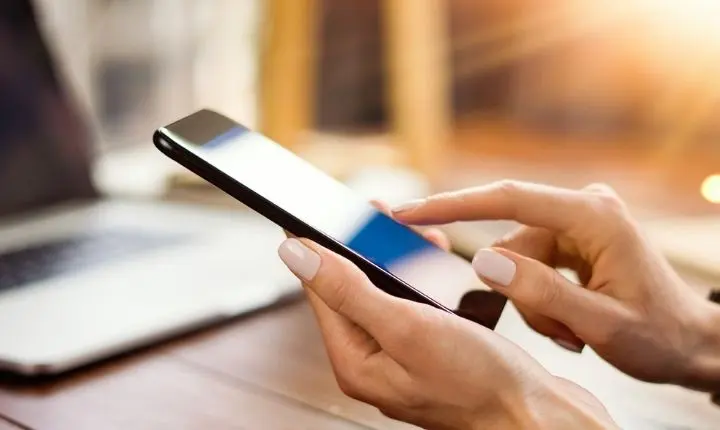 Persona utilizando un teléfono celular para realizar operaciones bancarias y proteger sus datos financieros