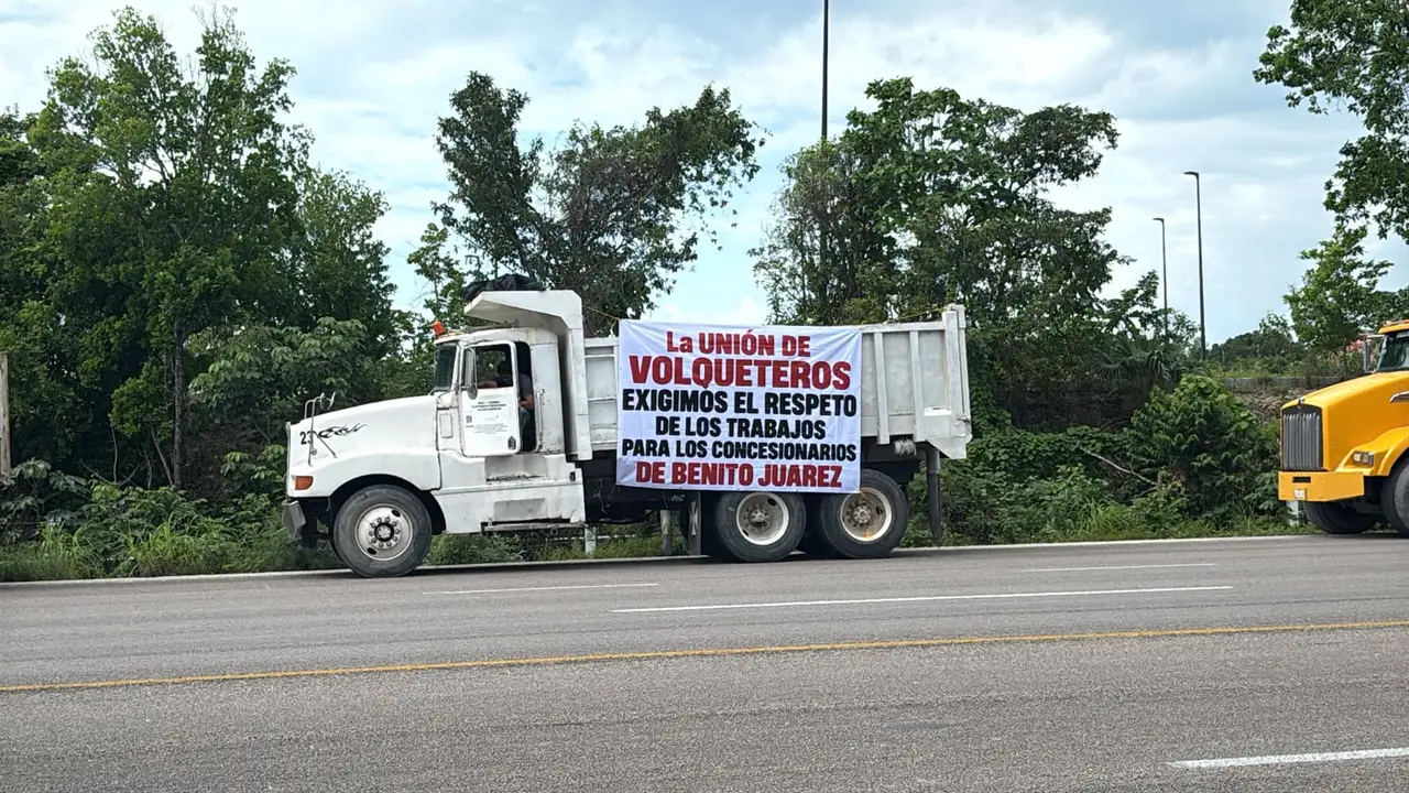 Operadores de camiones de carga se manifiestan frente a las oficinas del Tren Maya en Cancún para exigir un aumento en la tarifa por sus servicios.